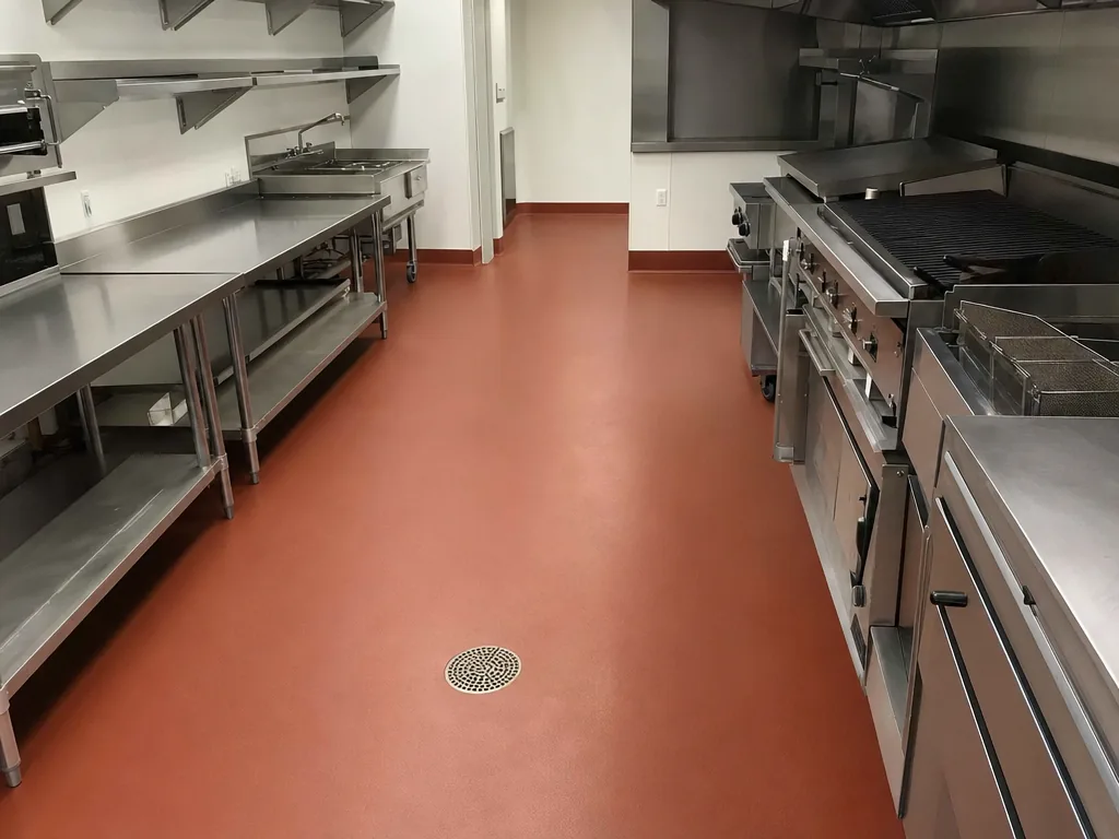 Commercial restaurant kitchen with a seamless terracotta resin floor and integral cove base